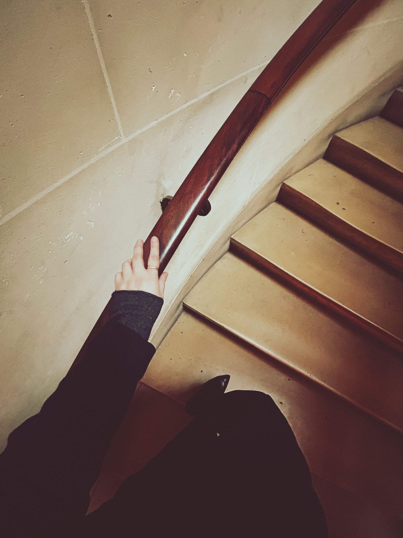 Hand holding a wooden handrail while walking down a staircase